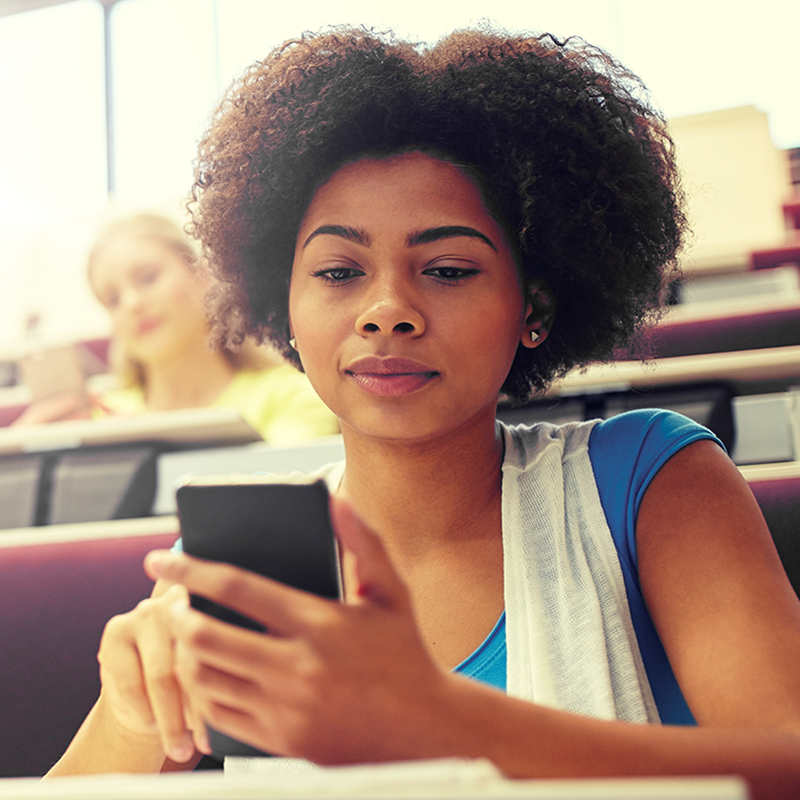 A young Black woman using her cellphone.