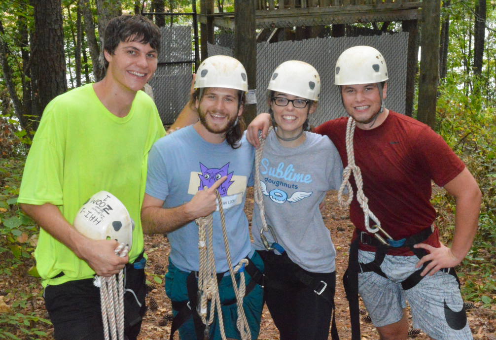 Three young men and a young woman at a challenge course.