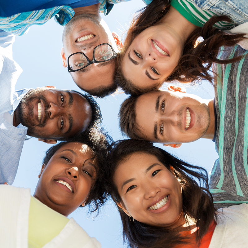 Smiling multi-ethnic friends standing in circle.